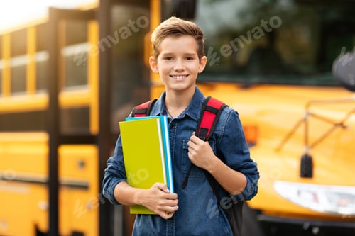 Preview: Back To School. Happy smiling preteen boy standing near school bus