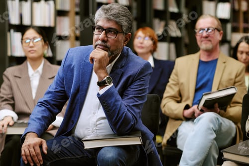 Preview: Middle Aged South Asian Man Listening Attentively during Book Presentation Event
