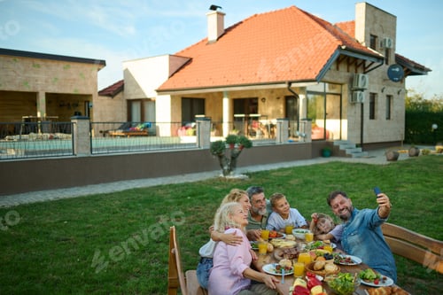 Preview: Happy family taking selfie while having lunch together in their backyard