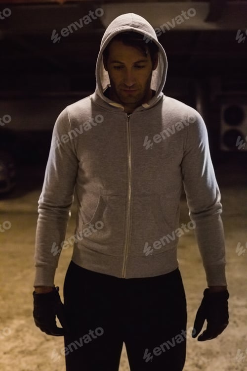 Preview: Man in hood jacket standing while looking down on black background