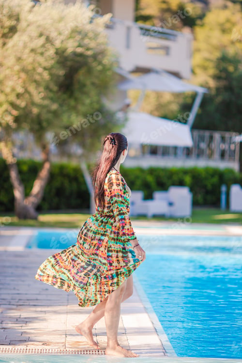 Preview: Woman relaxing by the pool in a luxury hotel resort enjoying perfect beach holiday vacation