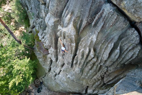 Preview: Strong child climber climbing steep wall of rocky mountain. Young boy overcoming difficult route