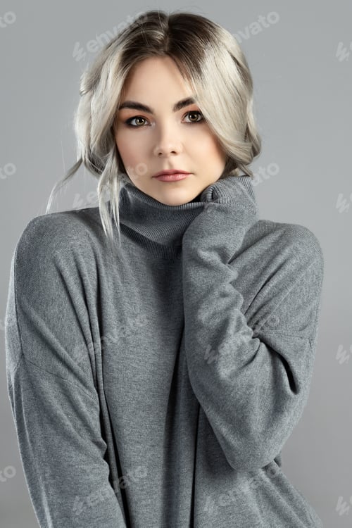 Preview: Young cute woman with blond hair wearing turtleneck jumper is posing in studio