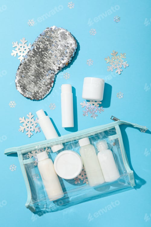 Preview: Cosmetic bottles in bag and sleep mask on blue background, top view