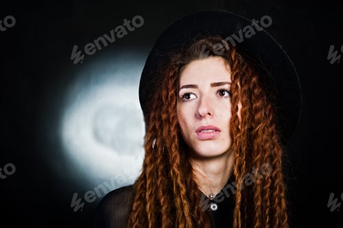 Preview: Studio shoot of girl in black with dreads and hat at black background.