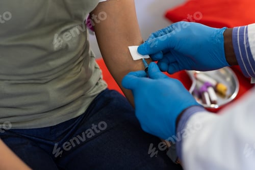 Preview: African american male doctor and biracial female patient collectiong blood at doctor's office