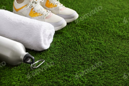 Preview: Bottle of water, sneakers, towel and space for text on artificial grass. Fitness equipment