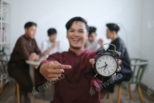 Preview: Asian Muslim Man Holding Alarm Clock Showing Iftar Time