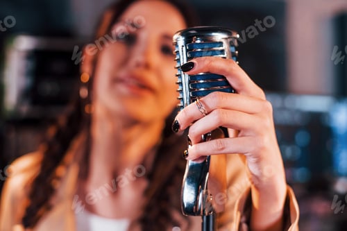 Preview: Close up view of microphone. Young beautiful female performer rehearsing in a recording studio