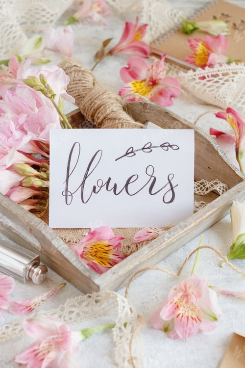 Preview: Card with handwritten text FLOWERS on a wooden tray between pink flowers