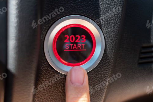 Preview: Finger press a car ignition button with 2023 START text inside automobile.