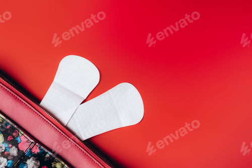Preview: sanitary napkin stick out from the bag and in the corner are beautiful peonies on a red background