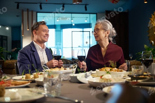Preview: Man and woman holding glasses with red wine toasting celebrating New Years Eve