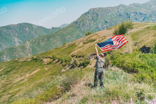 Preview: On the mountain, man in military uniform holding an American flag