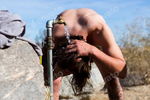 Preview: Young man washing hair under campsite tap, Anza-Borrego Desert State Park, California, USA