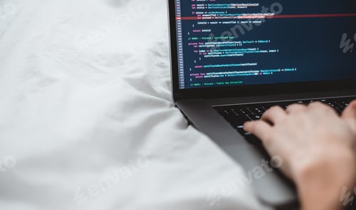 Preview: Young female programmer writes program code on a computer laptop in the bed at home. remote work