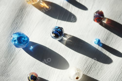 Preview: Group of glass beads of various colors and shapes and their long shadows
