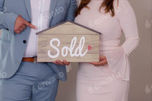 Preview: Couple holding a house-shaped paper with the word sold printed on it