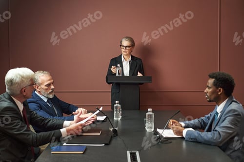 Preview: Middle Aged Caucasian Woman Addressing Diverse Male Politicians at Meeting