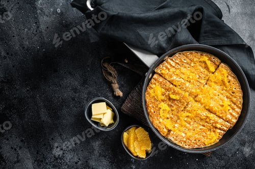 Preview: Cooking of French crepe Suzette with orange sauce in a skillet. Black background. Top view.