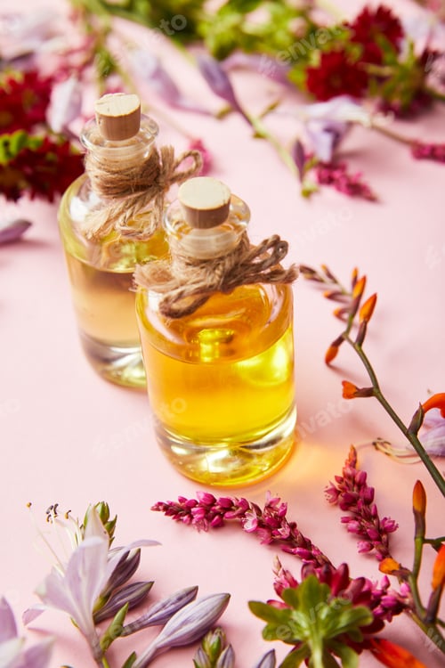 Preview: bottles with oil near wildflowers on pink background