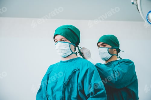 Preview: Portrait of male and female surgeon doctors wearing sterile gown with mask and gloves