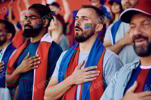 Preview: Group of sports fans with hand on heart singing national anthem during championship at the stadium.