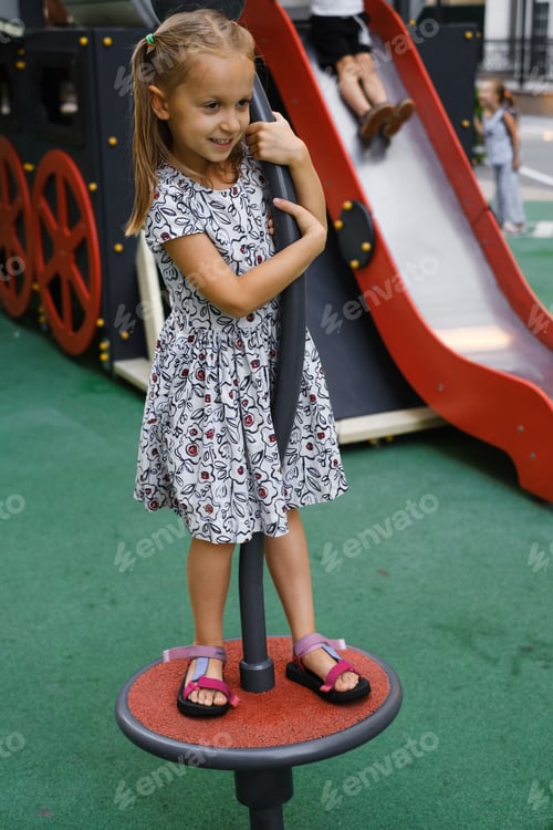 Preview: Child playing on the playground in the city in summer