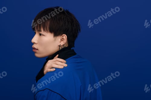 Preview: Captivating young asian man in a striking blue backdrop showcasing modern style and elegance