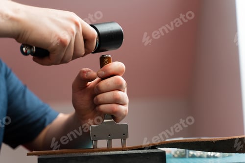 Preview: Creating handmade belt holes. Artisan works on leather strap with punch tool