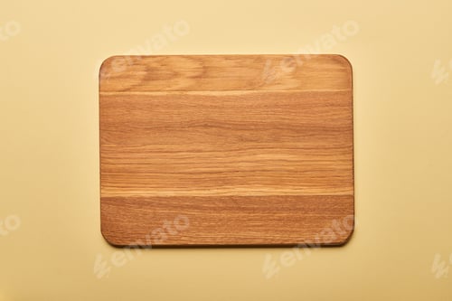 Preview: top view of empty wooden chopping board on yellow background