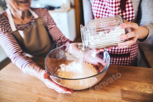 Preview: An elderly grandmother with an adult granddaughter at home, baking.