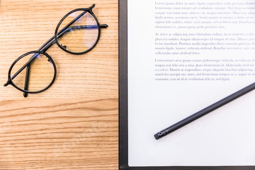 Preview: top view of eyeglasses, pencil and notepad with documents on wooden surface