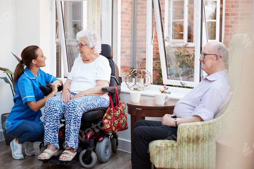 Preview: Male And Female Residents Sitting In Chair And Talking With Nurse In Retirement Home
