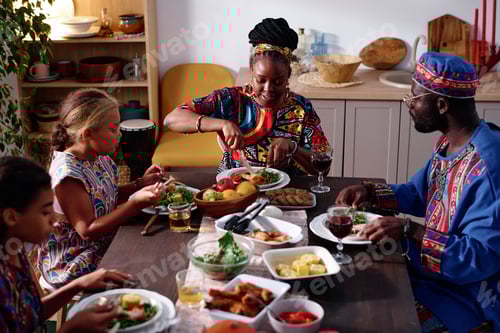 Preview: African American family of four in ethnic apparel sitting by festive table