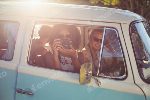 Preview: Woman taking photograph while travelling in campervan