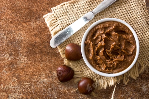 Preview: Chestnut cream in bowl with chestnuts and knife on rustic background