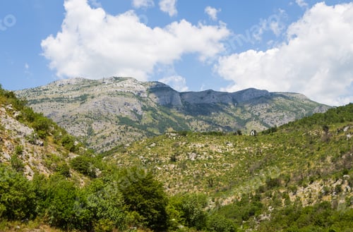 Preview: Scenic view of mountainous landscape with lush greenery under a blue sky.