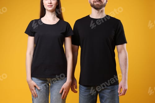 Preview: Woman and man wearing blank black t-shirts on orange background, closeup. Mockup for design