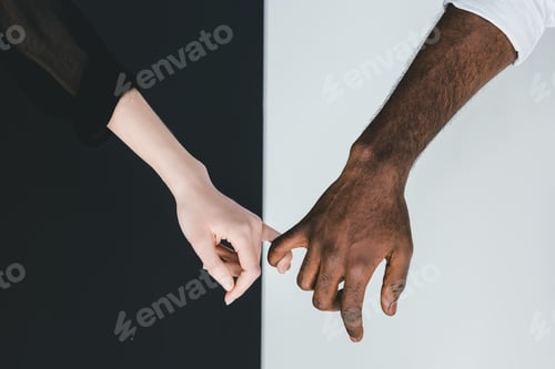 Preview: cropped image of african american boyfriend and girlfriend holding fingers near black and white wall
