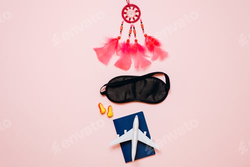 Preview: On a pink background are things for travel: passport, airplane, blindfold, earplugs, amulet