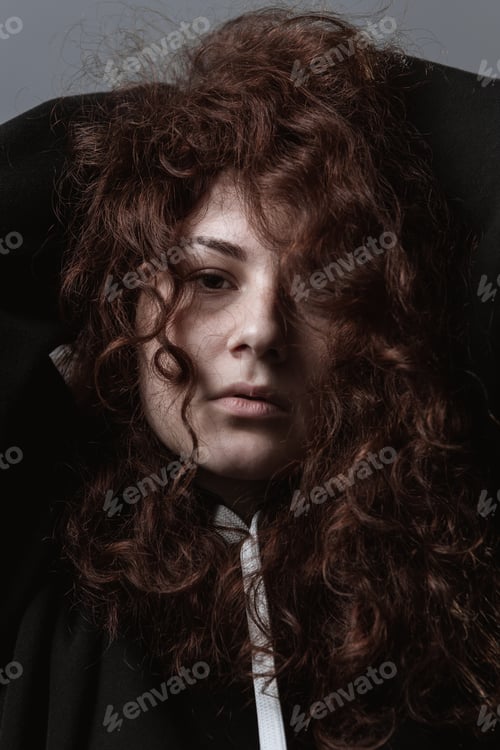 Preview: Portrait Of A Beautiful Curly-Haired Girl With Redheads On A Gray Background