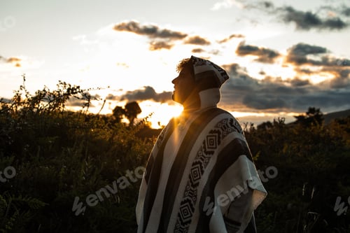 Preview: Multiracial Latino young man in poncho posing at sunset in the Ecuadorian Andes