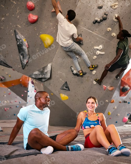 Preview: Male And Female Climbers Taking A Break And Talking By Climbing Wall In Indoor Activity Centre