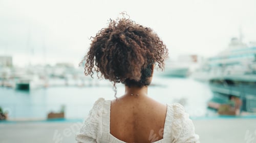 Preview: Closeup of a young woman in glasses stands in the seaport and looks at the ships.