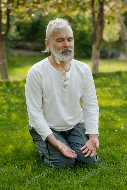 Preview: Senior bearded man in casualwear sitting on knees with his palms open
