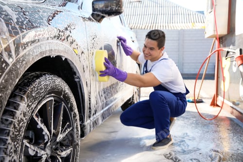 Preview: Worker cleaning automobile with sponge at car wash