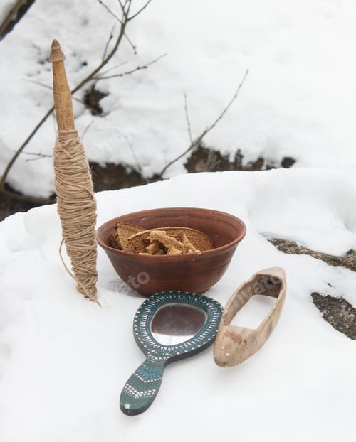 Preview: Spindle, mirror and clay plate with bread in the snow. Still life.