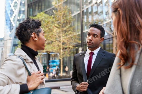 Preview: Three millennial business colleagues standing on the street talking, low angle, close up