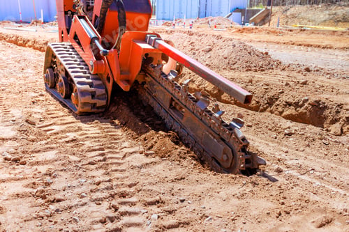 Preview: Excavator laying groundwork for construction project under bright sunlight at a rural site